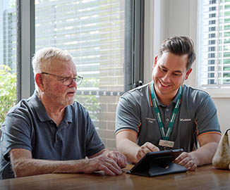 Home Care worker helps client with devices