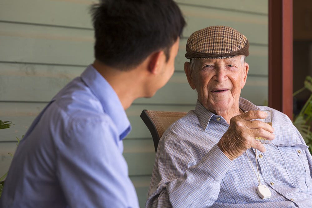 A carer sitting on the porch with a resident and chatting inside Whiddon Hornsby's aged care home.