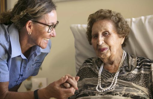 A carer holding a resident's hand, highlighting the dedication of Whiddon carers at Whiddon's aged care home in Beaudesert.