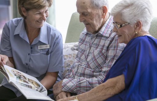A Whiddon carer enjoying a book with two residents at Whiddon's Belmont nursing home.