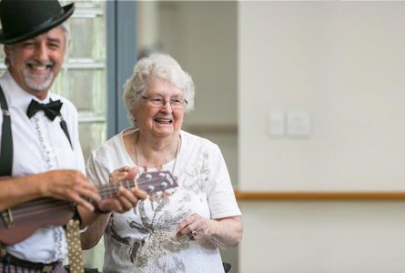 A resident dancing happily with Morrie who is playing a ukulele at Whiddon's nursing home in Maitland.