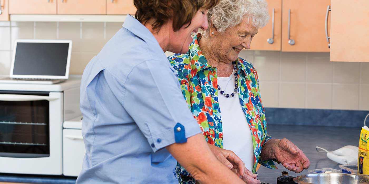 A carer and resident enjoying cooking together at Whiddon's community care home on the mid north coast.