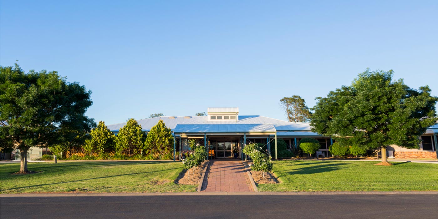 Whiddon Wee Waa's front entrance, surrounded by tall trees and a manicured lawn.