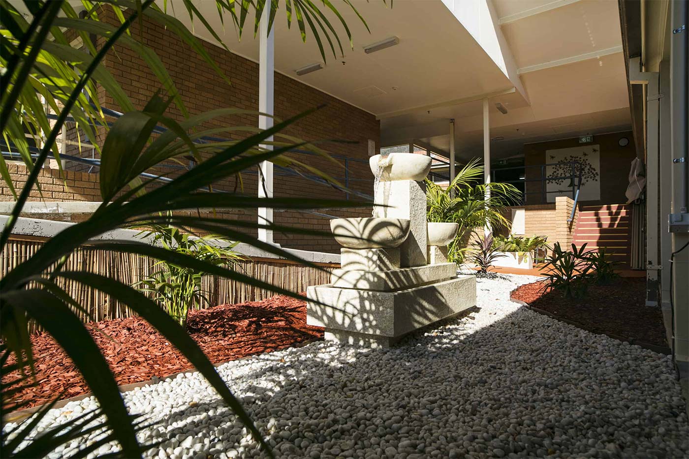 Front entrance of Whiddon Laurieton's residential aged care home, fitted with a water fountain and lush plants.
