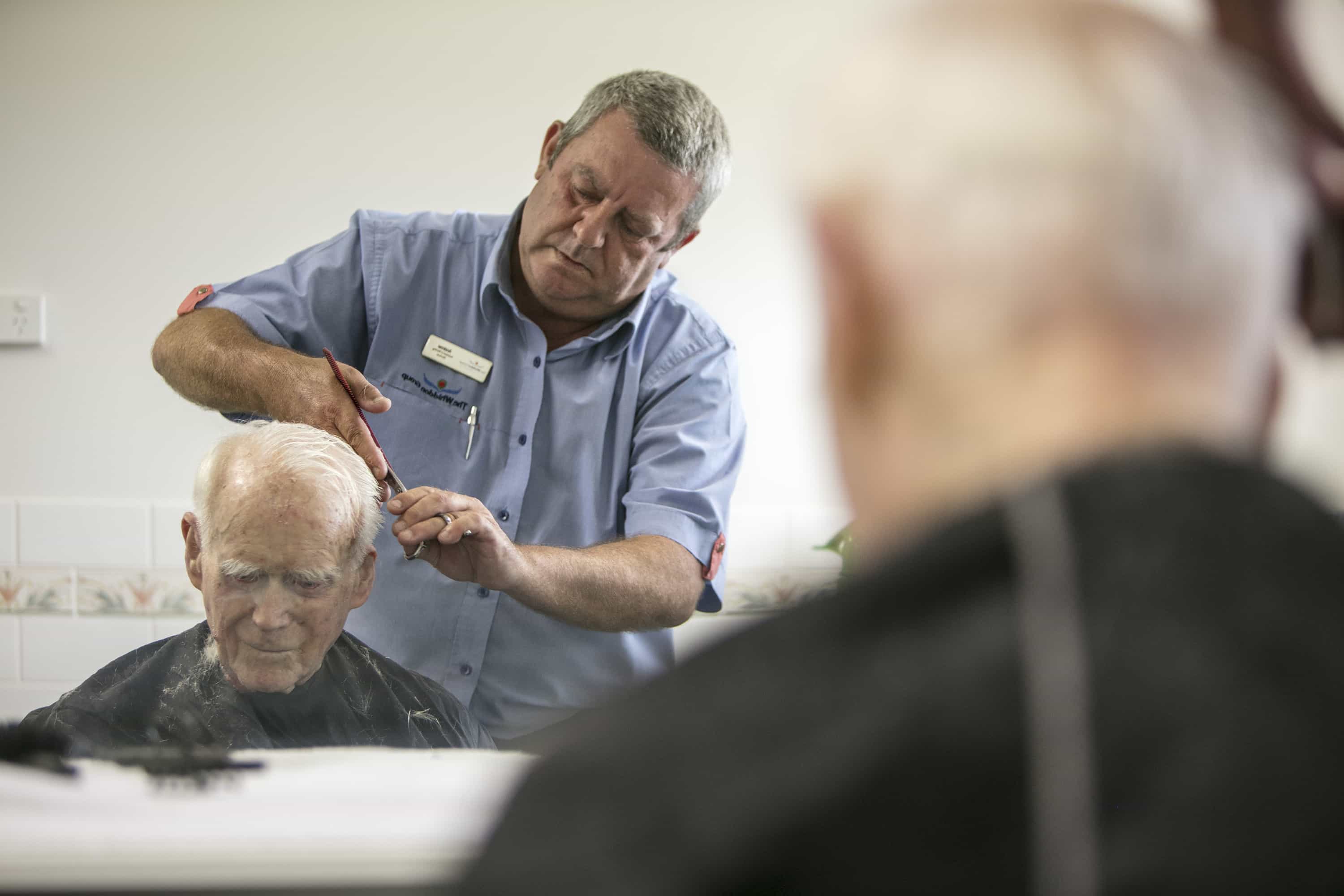 A Whiddon carer giving a resident a haircut at Whiddon Maclean.