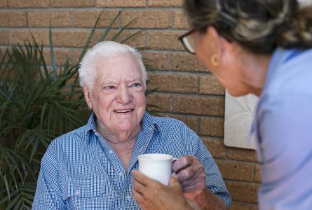 A Whiddon carer handing a cup of tea to a resident at Whiddon's Easton Park, an aged care home in Glenfield.