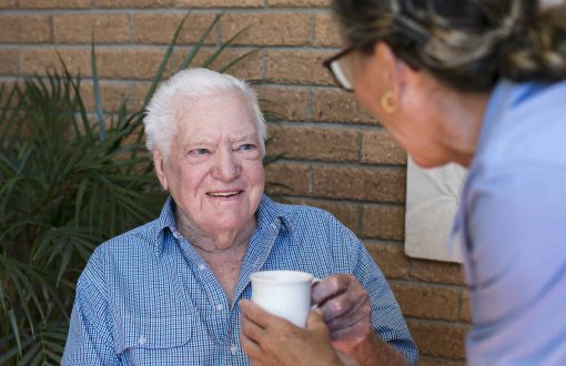 A Whiddon carer handing a cup of tea to a resident at Whiddon's Easton Park, an aged care home in Glenfield.