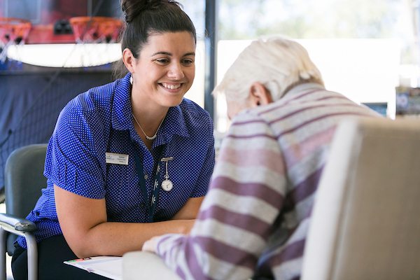 A Whiddon carer chatting happily with a resident at the Whiddon Belmont nursing home.