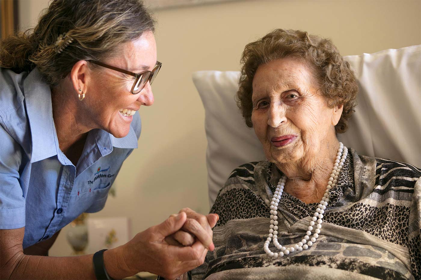 A carer holding a resident's hand, highlighting the dedication of Whiddon carers at Whiddon's aged care home in Beaudesert.