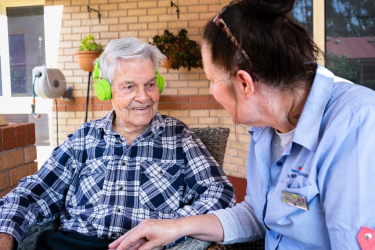 A Whiddon carer spending time and listening to music with a resident.