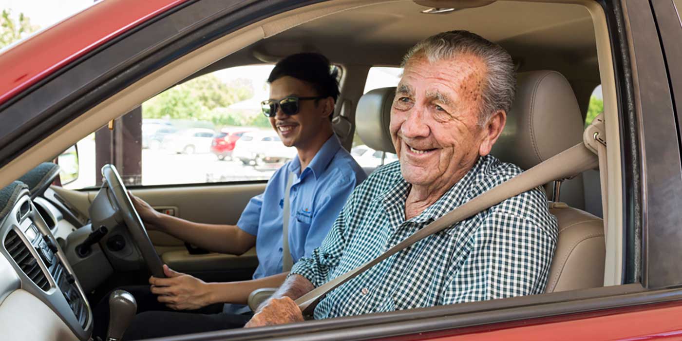 A carer with a resident enjoying a car ride as part of assisted transport services at Whiddon Narrabri.