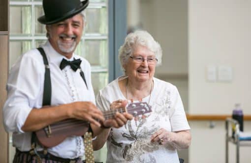 A resident dancing happily with Morrie who is playing a ukulele at Whiddon's nursing home in Maitland.