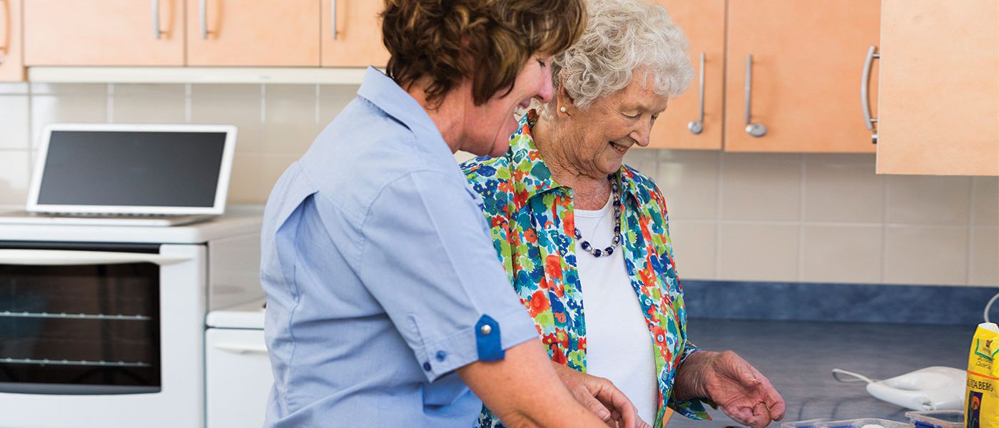 Care worker is helping to prepare a meal