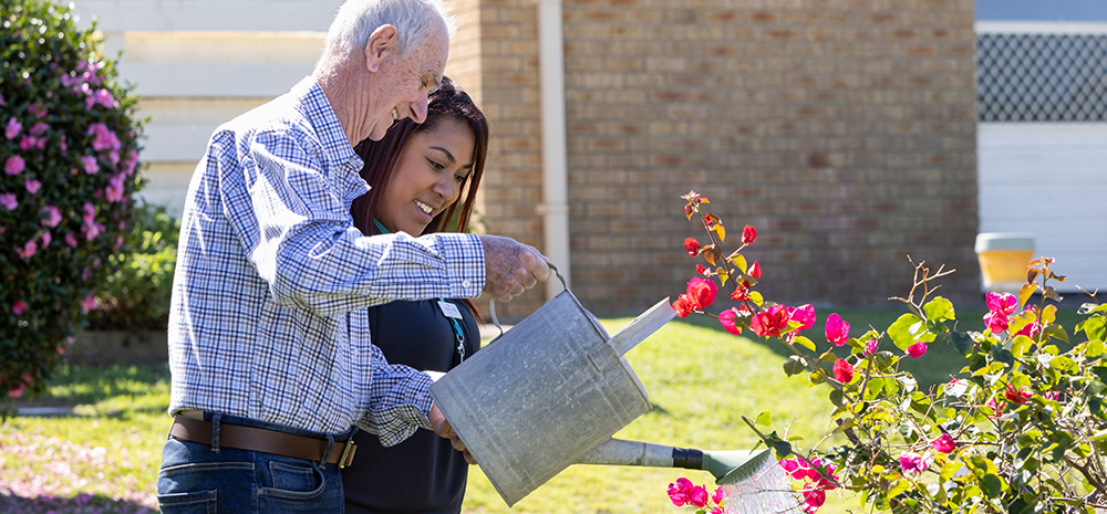 Whiddon Community Care Worker and Client watering a plant