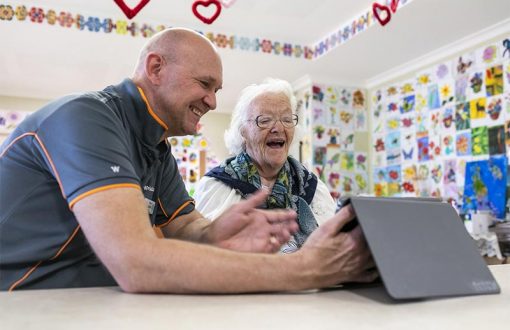 Whiddon Staff helping a resident with electronic device