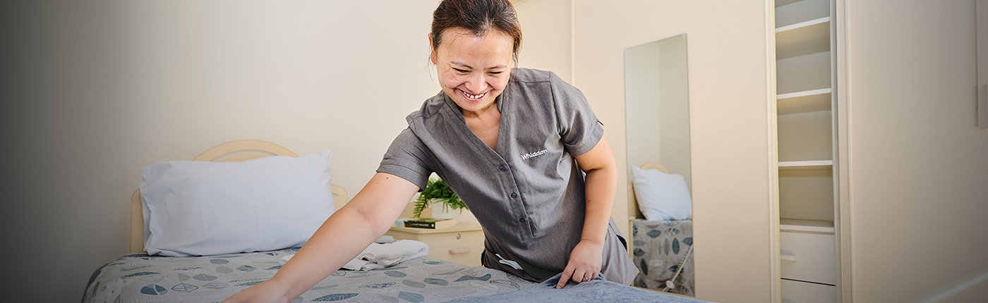 care worker making the bed of a resident