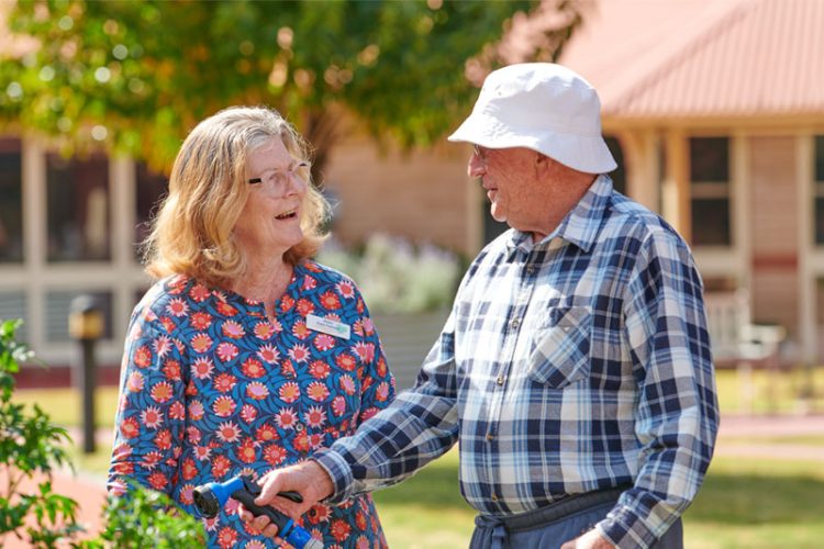 A Carer talkes to a residend while he is watering the garden
