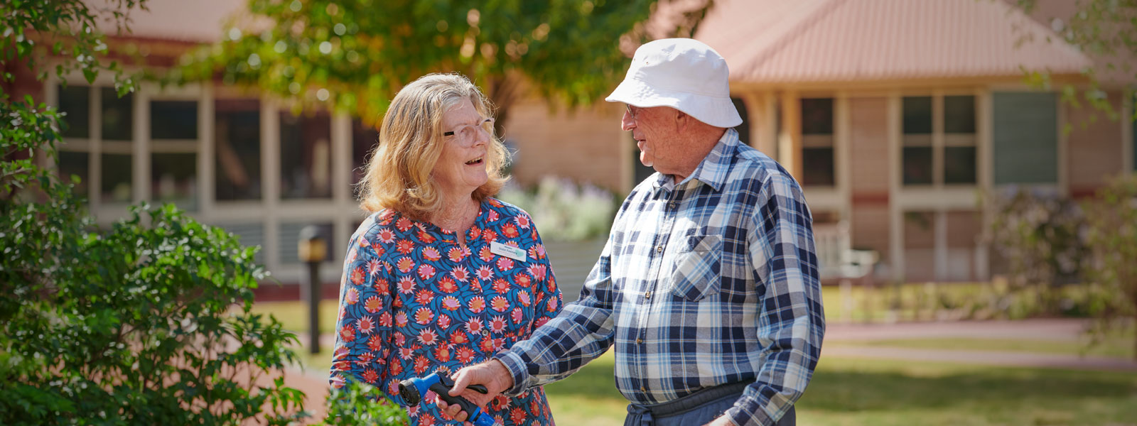A Carer talkes to a residend while he is watering the garden