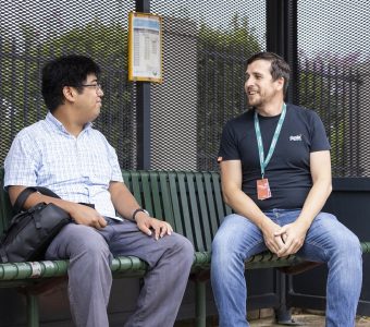 Disability participant, Chris is waiting for the bus at the bus stop with his carer, Andrew