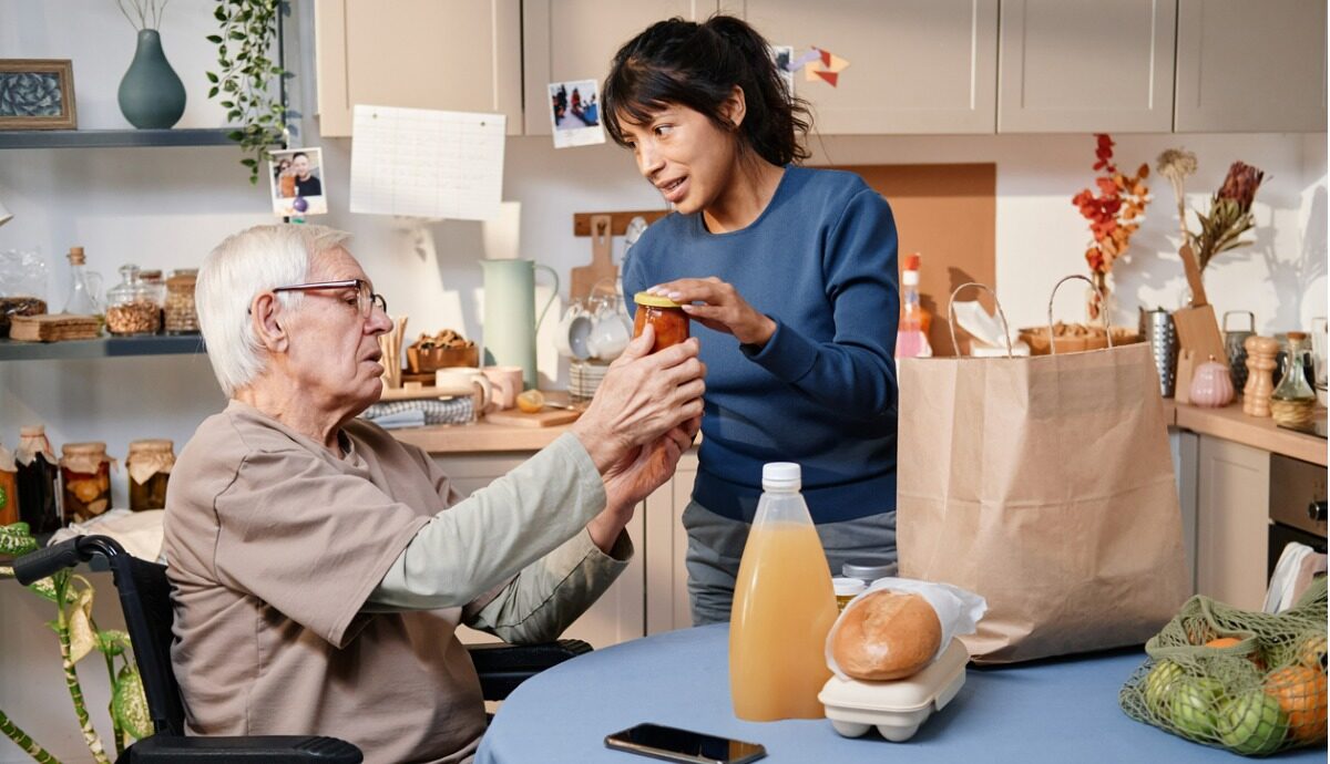 home carer unpacking groceries for older adult.