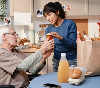 home carer unpacking groceries for older adult.