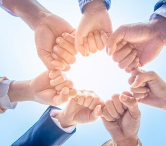 group of different workers putting their fists together in a circle.