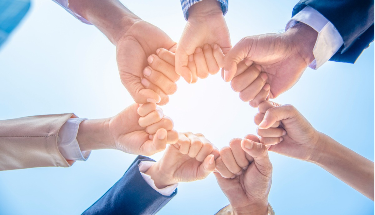 group of different workers putting their fists together in a circle.