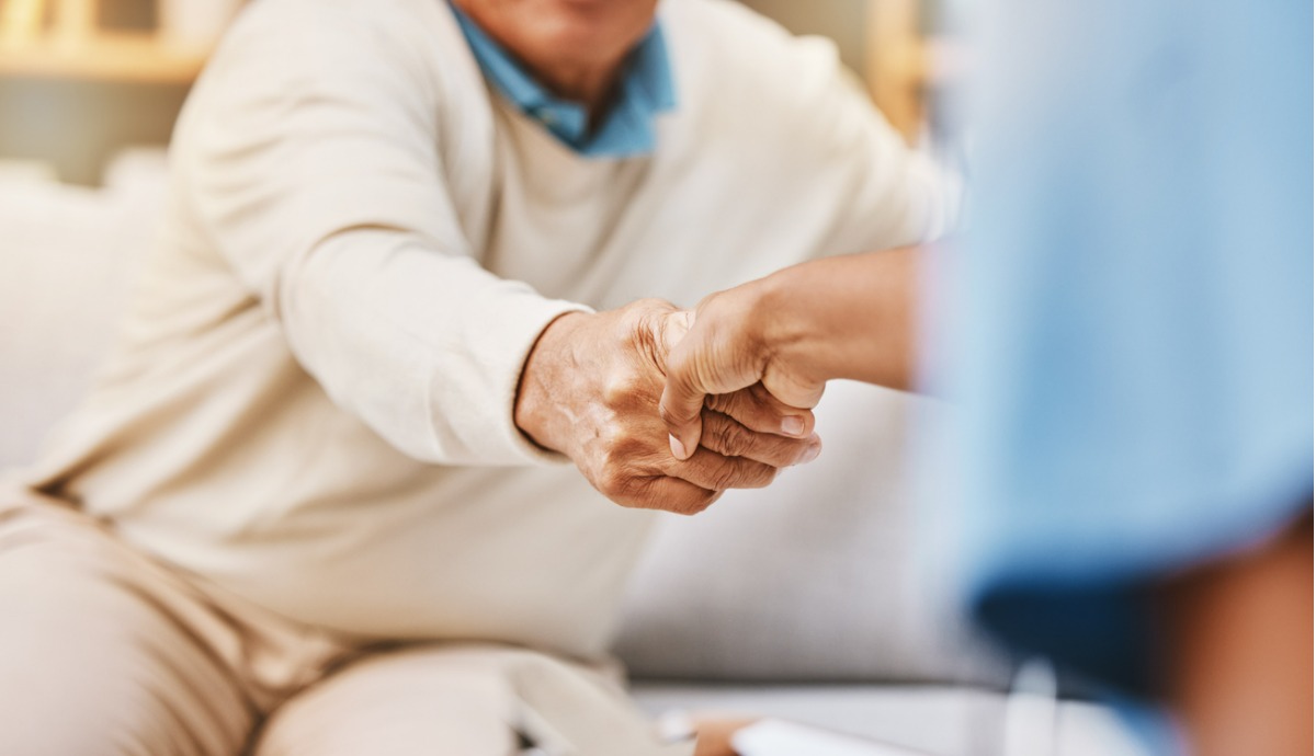 older adult shaking the hand of an aged care worker