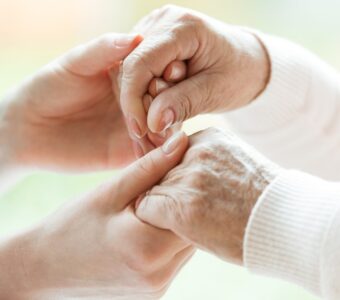 caregiver holding older persons hands