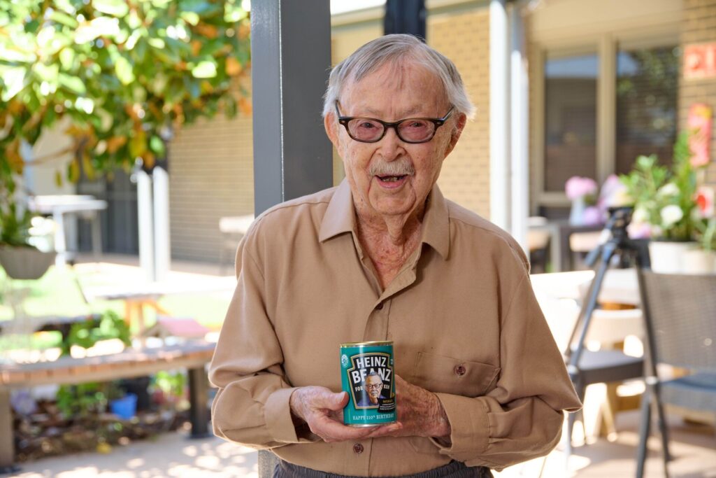 Ken Weeks, smiling and holding his can of personalised Heinz beans.