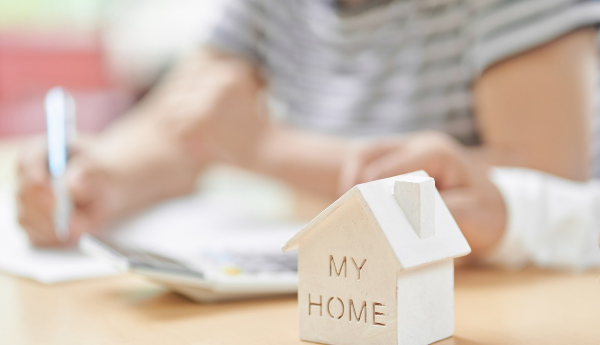 elderly couple signing document with model of their home in front of them