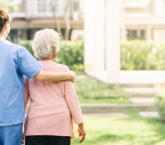 aged care worker walking with older adult outside