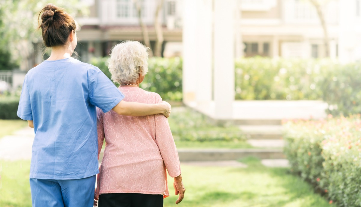 aged care worker walking with older adult outside