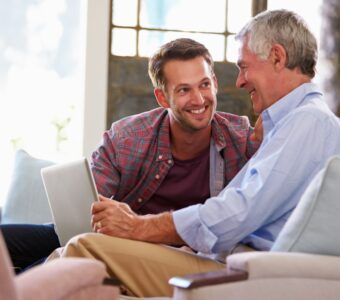 adult son talking with older father holding computer