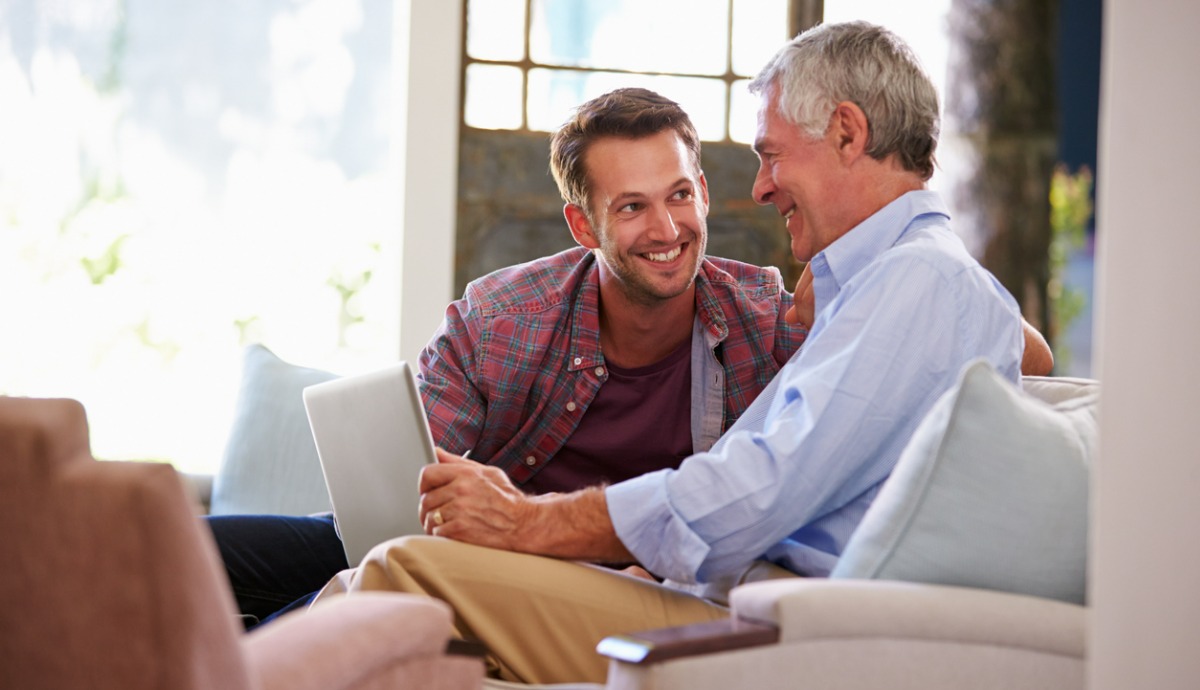 adult son talking with older father holding computer