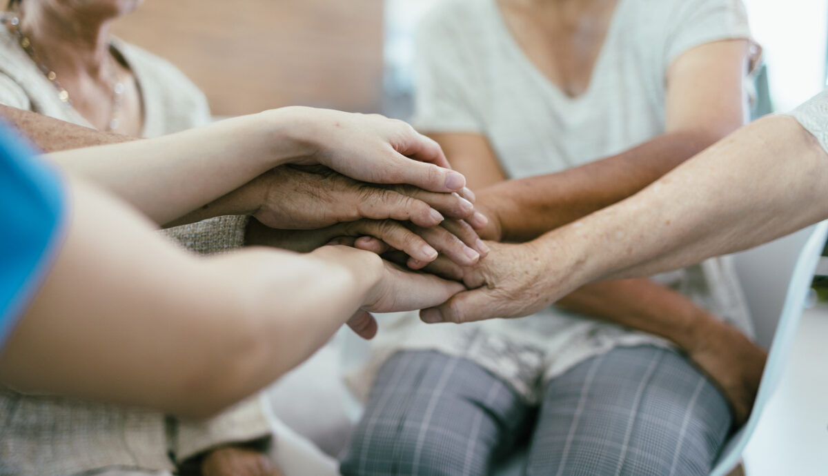 Background of older bare hands join together with nurse