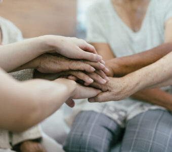 Background of older bare hands join together with nurse