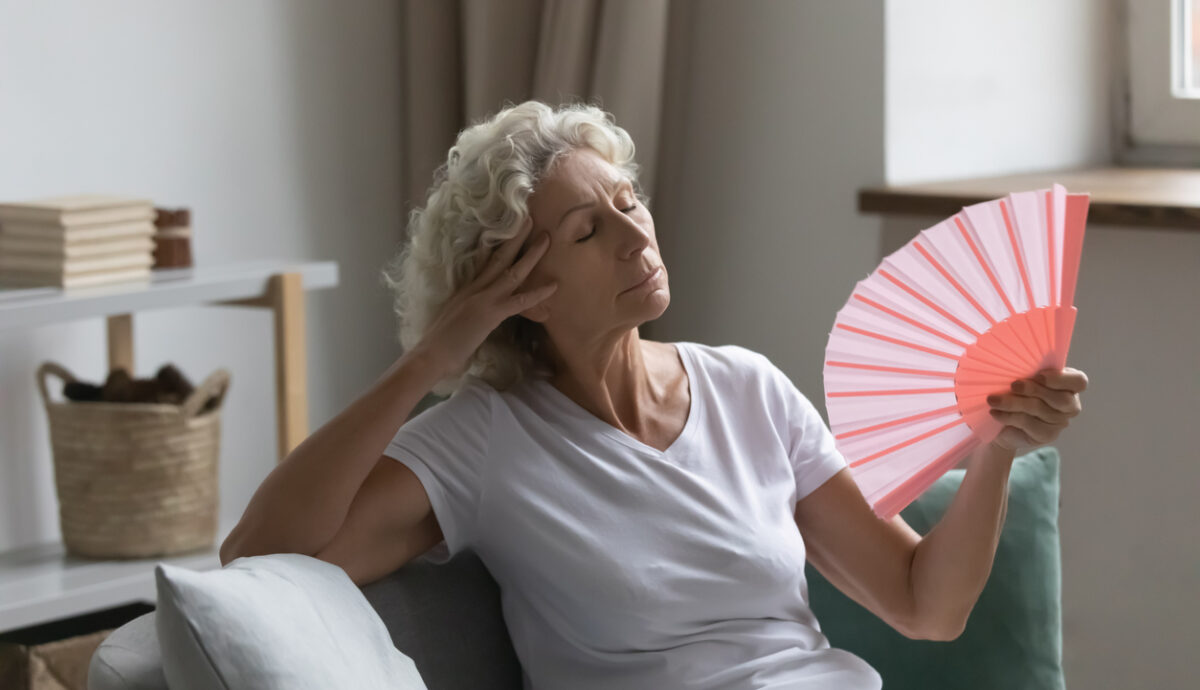 Overheated older woman fanning herself to cool down from the heat