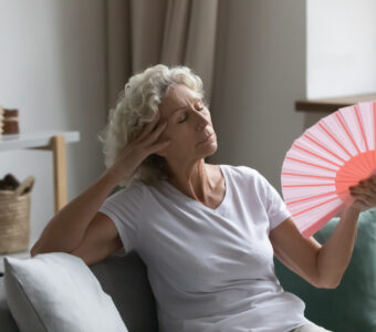 Overheated older woman fanning herself to cool down from the heat