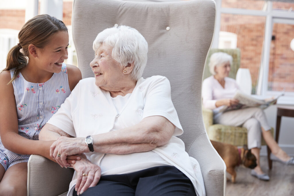 young girl talking with older aged care resident sitting on chair