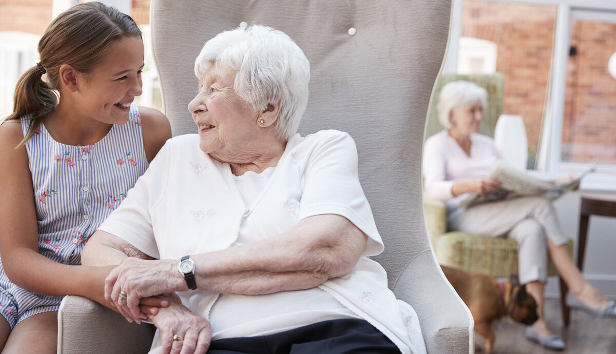 young girl talking with older aged care resident sitting on chair