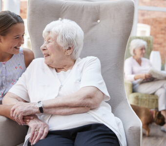 young girl talking with older aged care resident sitting on chair