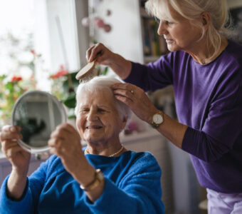 personal care worker brushing the hair of an older woman