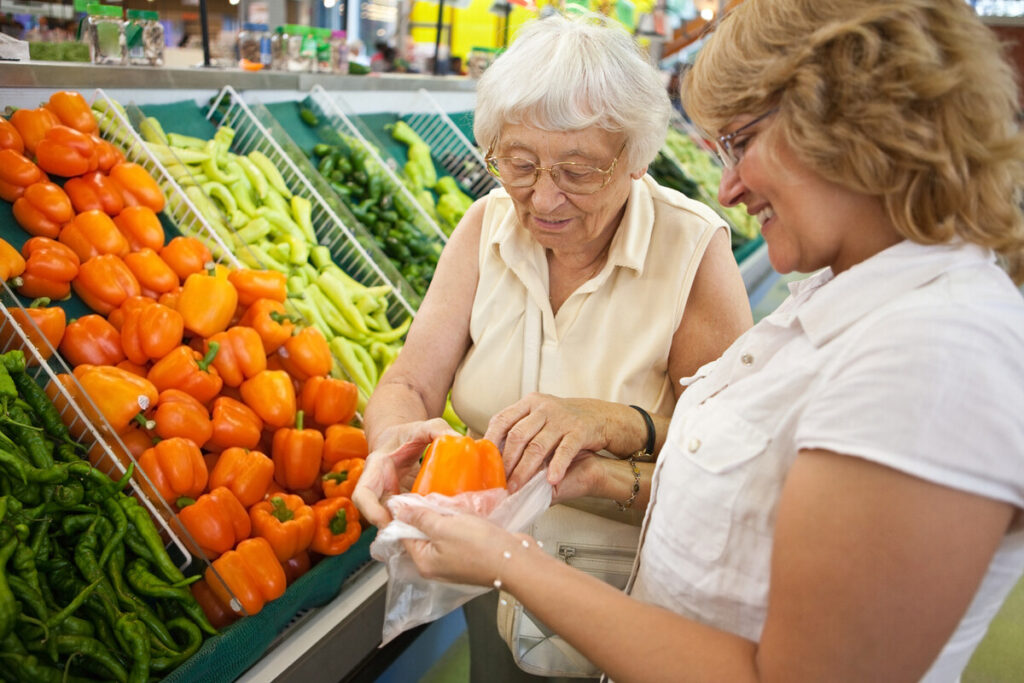 aged care volunter helping older woman with groceries