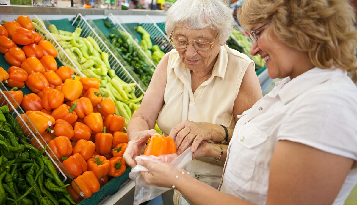 aged care volunter helping older woman with groceries