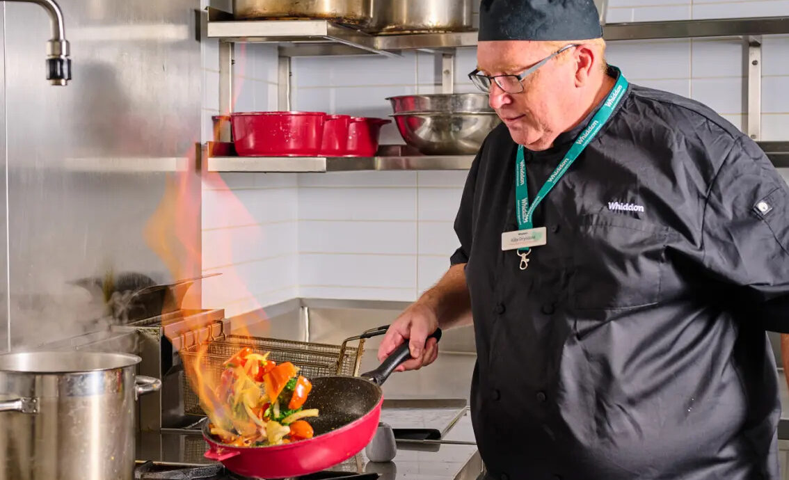 chef cooking over stove in aged care kitchen