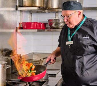 chef cooking over stove in aged care kitchen