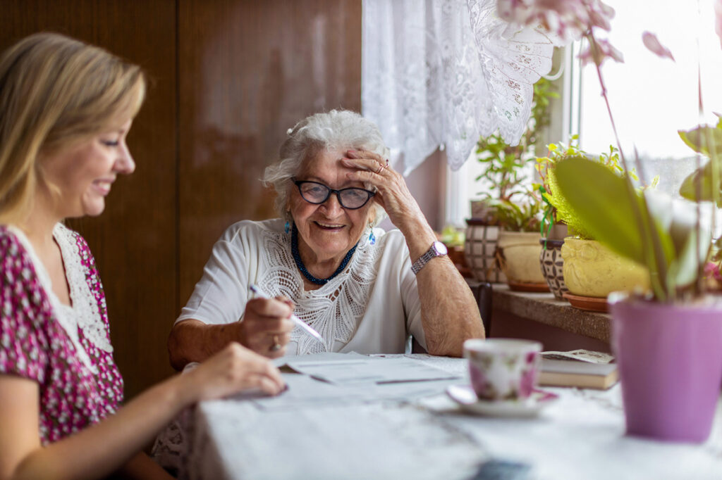 younger woman helping senior mother with paperwork