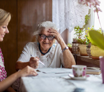 younger woman helping senior mother with paperwork