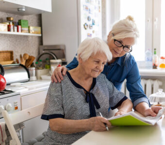 Mature woman helping elderly mother with paperwork
